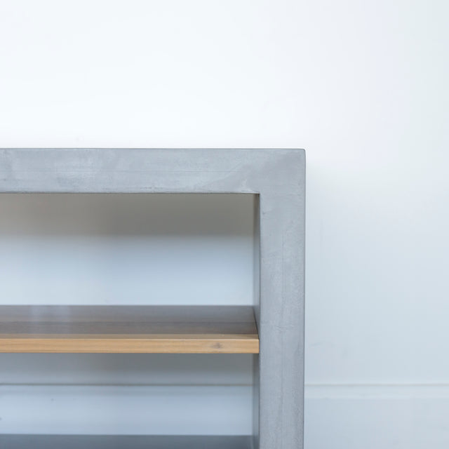 Image rapprochée d'un Meuble TV moderne en bois de noyer et beton gris avec tiroirs et etageres ouvertes.