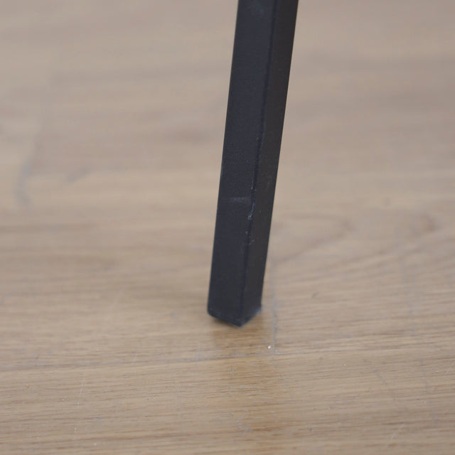 image rapprochée d'une chaise vintage cognac avec assise matelassee et pieds en metal noir.