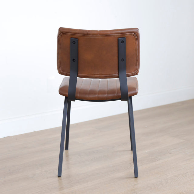 chaise vintage cognac avec assise matelassee et pieds en metal noir.