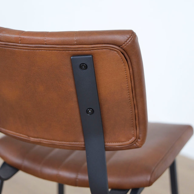 chaise vintage cognac avec assise matelassee et pieds en metal noir.