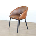 Chaise moderne en cuir cognac avec dossier incurvé et pieds noirs élegants.