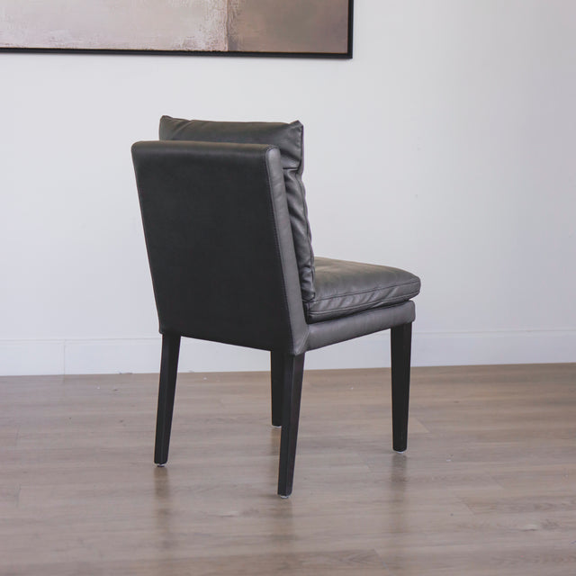 chaise en cuir noir avec coussins rembourrés et pieds en bois sombre.