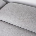 gros plan sur le tissu gris clair texturee du coussin de siege de canape moderne.

