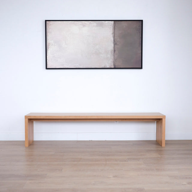 banc en bois clair au design minimaliste posé contre un mur blanc.