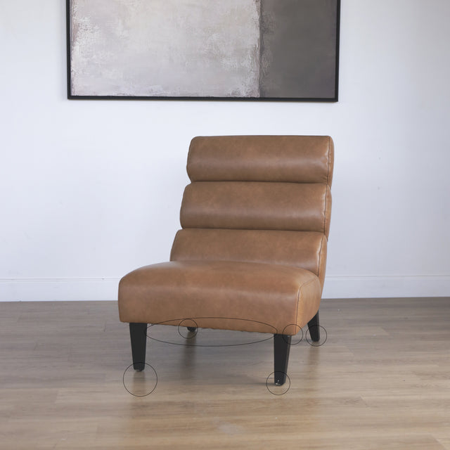 Fauteuil moderne en cuir végane cognac avec pieds noirs sur sol en bois avec cercles indiquant les défauts.