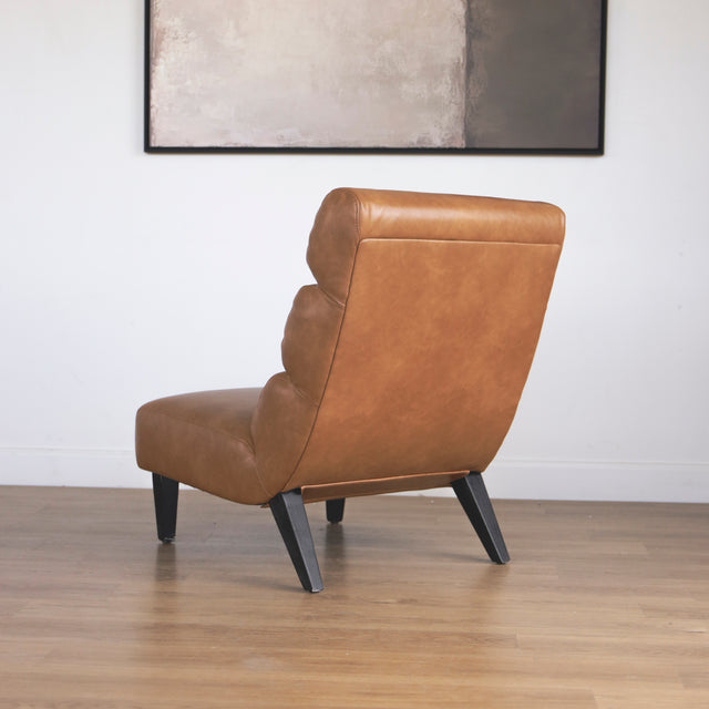 fauteuil moderne en cuir végane cognac avec pieds noirs sur sol en bois.