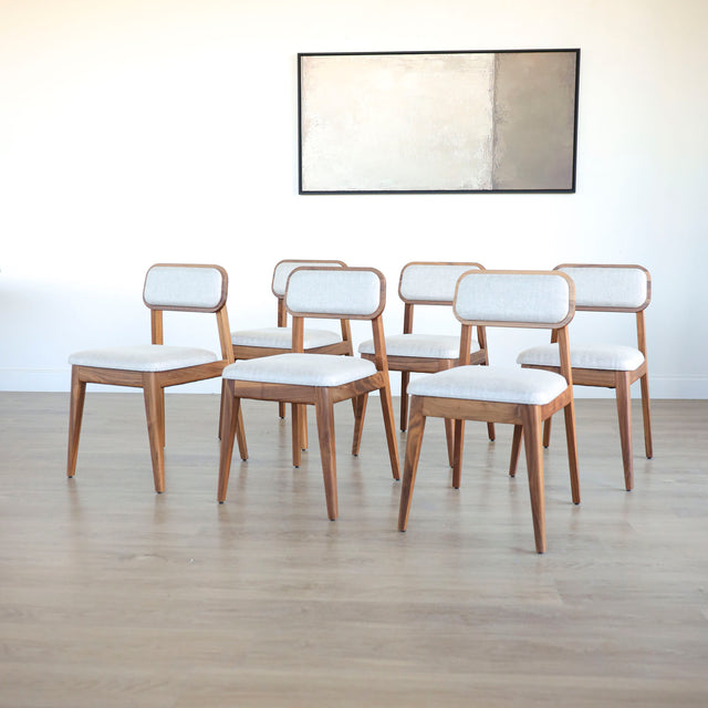 Lot de six chaises en bois de noyer avec assise et dossier rembourres en tissu beige.