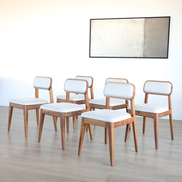 Lot de six chaises en bois de noyer avec assise et dossier rembourres en tissu beige.