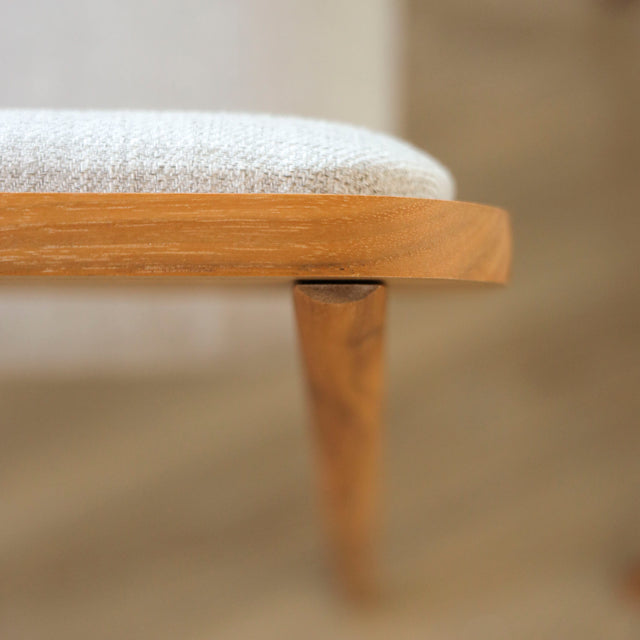 image rapprochée d'une chaise en bois de noyer avec assise et dossier rembourres en tissu beige.