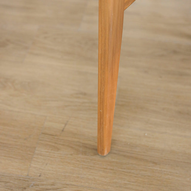 image rapprochée d'une chaise en bois de noyer avec assise et dossier rembourres en tissu beige.