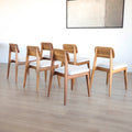 Lot de six chaises en bois de noyer avec assise et dossier rembourres en tissu beige.