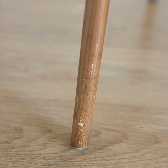 Image rapprochée d'une patte en bois d'un lot de trois chaises style scandinave avec structure en bois et assise beige rembourree.