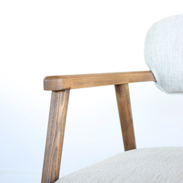 Image rapprochée d'un appuie bras en bois d'un lot de trois chaises style scandinave avec structure en bois et assise beige rembourree.