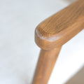 Image rapprochée d'un appuie bras en bois d'un lot de trois chaises style scandinave avec structure en bois et assise beige rembourree.