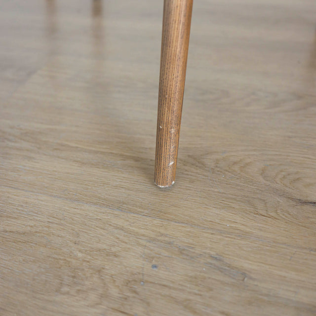 Image rapprochée d'une patte en bois d'un lot de trois chaises style scandinave avec structure en bois et assise beige rembourree.