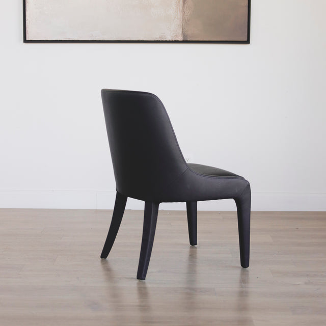 chaise contemporaine en cuir végane noir avec design incurve et pieds assortis.