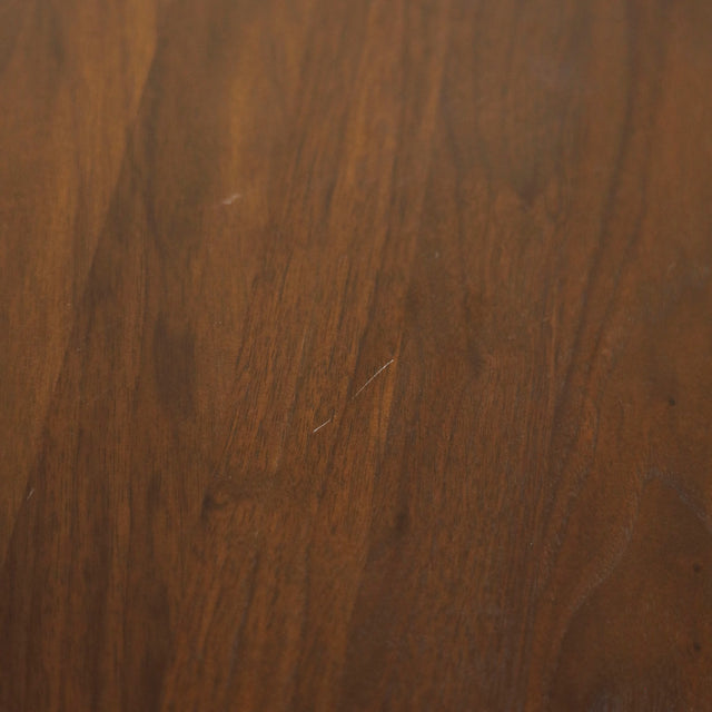 Image rapprochée comportant un défauts d'une table ronde en noyer massif avec pied central croise au design contemporain.