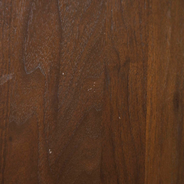 Image rapprochée d'une table ronde en noyer massif avec pied central croise au design contemporain.