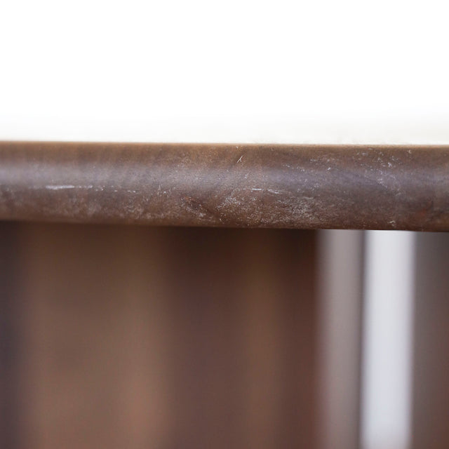 Image rapprochée d'une table ronde en noyer massif avec pied central croise au design contemporain.