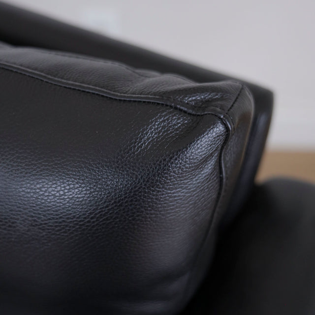 Image rapprochée d'un Fauteuil en cuir noir avec structure en bois style moderne.