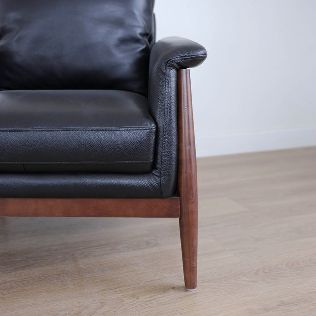Fauteuil en cuir noir avec structure en bois style moderne.