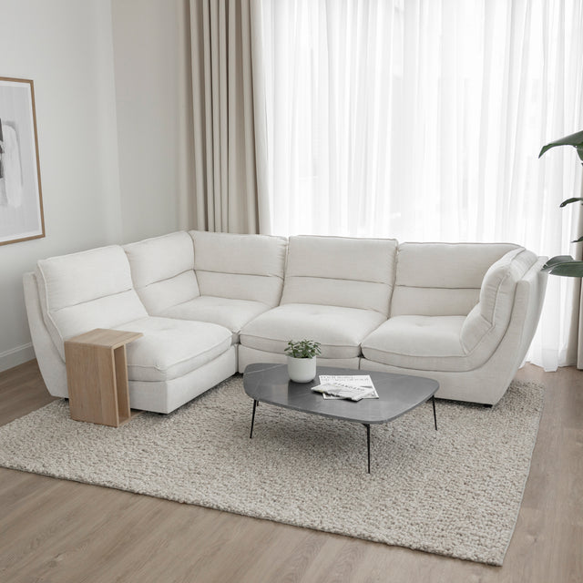 Canape sectionnel blanc moderne avec table basse noire et decor minimaliste sur tapis clair.