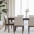Table de salle à manger en bois foncé avec chaises rembourrées en tissu beige, style contemporain.