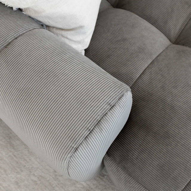 Sectionnel en velours côtelé brun avec assise profonde, design moderne dans un salon épuré.