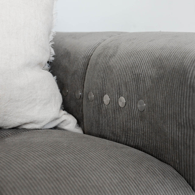 Sectionnel en velours côtelé brun avec assise profonde, design moderne dans un salon épuré.