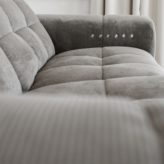 Sectionnel en velours côtelé brun avec assise profonde, design moderne dans un salon épuré.