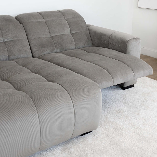 Sectionnel en velours côtelé brun avec assise profonde, design moderne dans un salon épuré.
