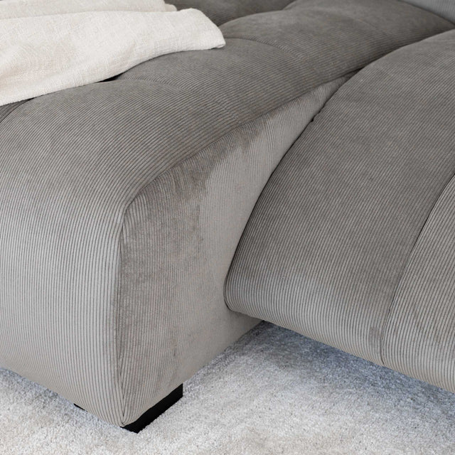 Sectionnel en velours côtelé brun avec assise profonde, design moderne dans un salon épuré.