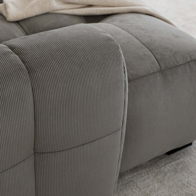 Sectionnel en velours côtelé brun avec assise profonde, design moderne dans un salon épuré.