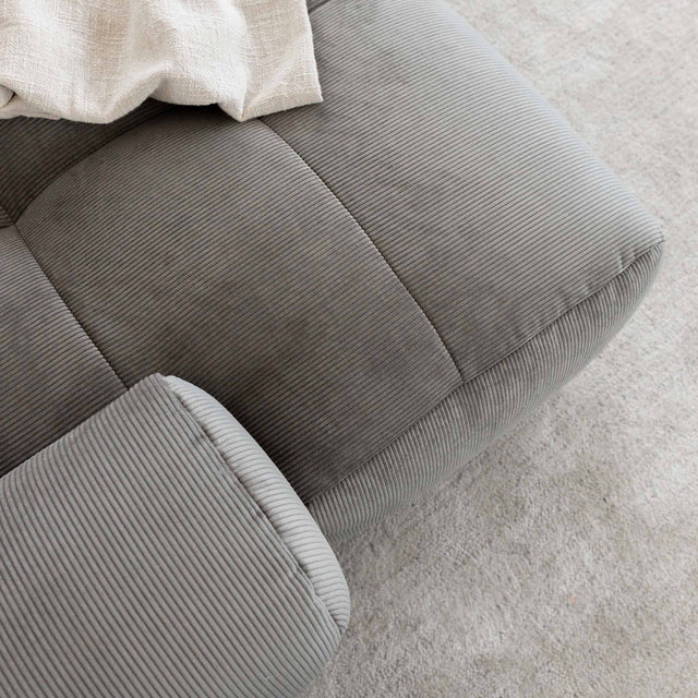 Sectionnel en velours côtelé brun avec assise profonde, design moderne dans un salon épuré.