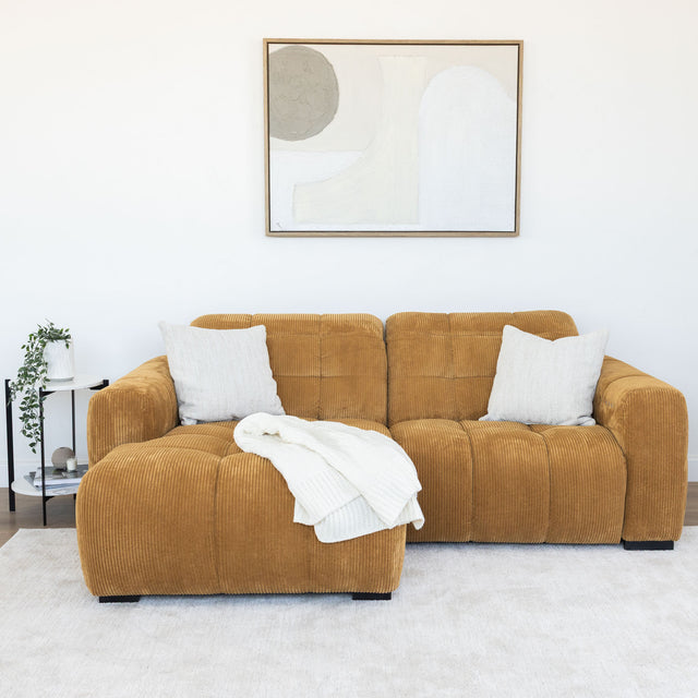 Sectionnel en velours côtelé camel, design moderne avec assise large dans un salon minimaliste.