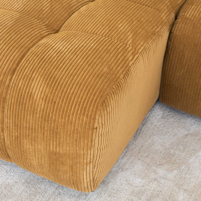 Sectionnel en velours côtelé camel, design moderne avec assise large dans un salon minimaliste.
