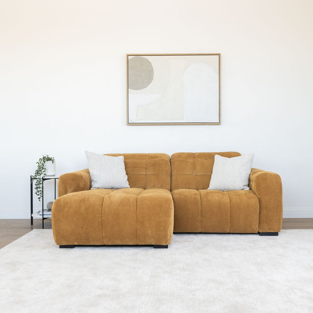 Sectionnel en velours côtelé camel, design moderne avec assise large dans un salon minimaliste.
