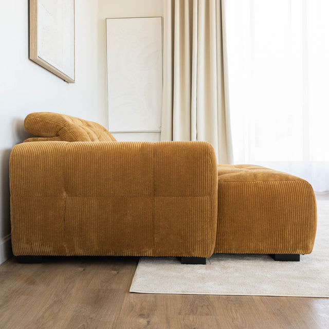 Sectionnel en velours côtelé camel, design moderne avec assise large dans un salon minimaliste.