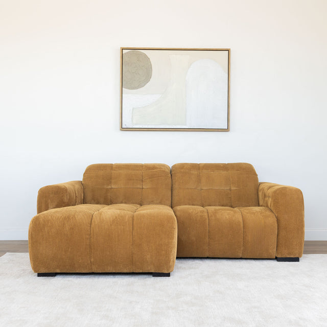 Sectionnel en velours côtelé camel, design moderne avec assise large dans un salon minimaliste.