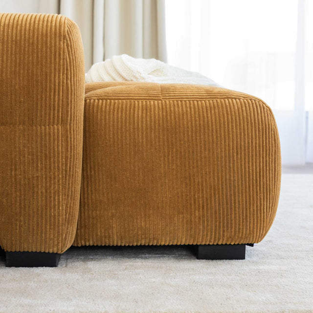 Sectionnel en velours côtelé camel, design moderne avec assise large dans un salon minimaliste.