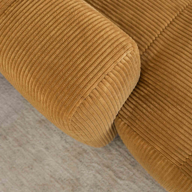 Sectionnel en velours côtelé camel, design moderne avec assise large dans un salon minimaliste.