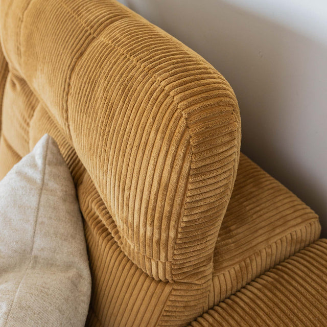Sectionnel en velours côtelé camel, design moderne avec assise large dans un salon minimaliste.