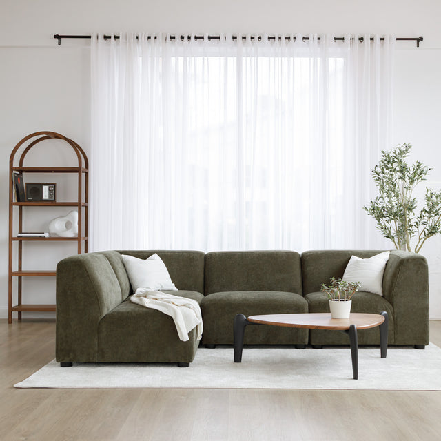 Sectionnel en tissu vert olive avec méridienne gauche, au design arrondi et contemporain dans un salon lumineux.