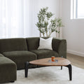 Sectionnel en tissu vert olive avec méridienne gauche, au design arrondi et contemporain dans un salon lumineux.