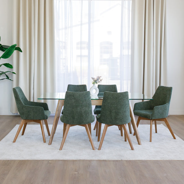 Chaise de salle à manger en tissu vert avec accoudoirs et pieds en bois, style moderne autour d’une table en verre.