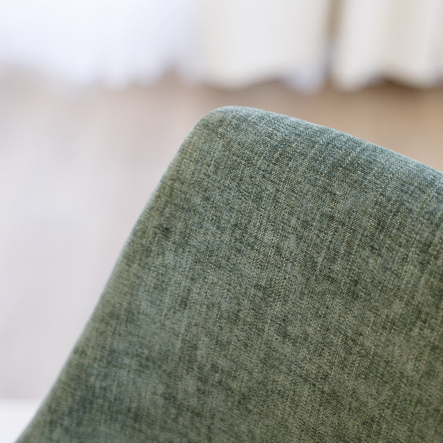 Chaise de salle à manger en tissu vert avec accoudoirs et pieds en bois, style moderne autour d’une table en verre.