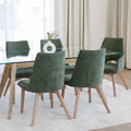 Chaise de salle à manger en tissu vert avec accoudoirs et pieds en bois, style moderne autour d’une table en verre.