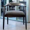 Chaise de salle à manger contemporaine avec accoudoirs noirs et assise rembourrée en tissu texturé gris.