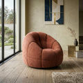 Fauteuil design arrondi terracotta en tissu, forme enveloppante dans un salon moderne lumineux.