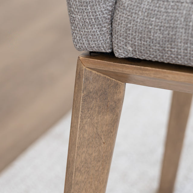 Chaise de cuisine en tissu beige avec pieds en bois naturel dans un intérieur moderne.